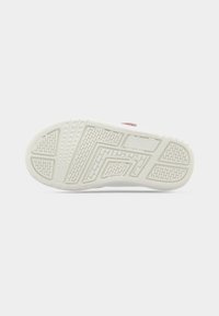 Semelle de chaussure en caoutchouc blanc texturé, présentant un motif en zigzag pour l'adhérence et un bord lisse. Accentuée par un design subtil.