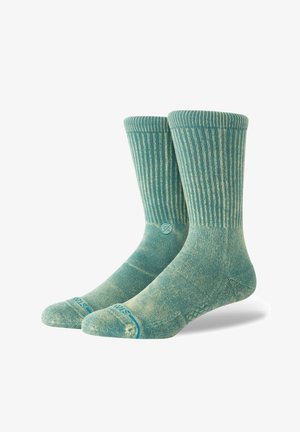 Șosete verde teal deschis cu textură ribletă, cu vârfuri și călcâie întărite. Prezintă un model subtil și un logo în apropierea gleznei.