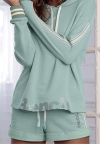 Mintgroene hoodie met witte trekkoorden en gestreepte boorden, gecombineerd met bijpassende shorts met een gedrukt logo en opgerolde zomen.