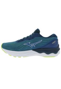 Zapatilla de running con una parte superior de punto azul transpirable, entresuela blanca y suela negra texturizada. Presenta detalles en verde lima en la suela.