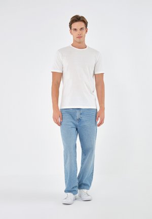 White crew-neck t-shirt, short sleeves, paired with light blue straight-leg jeans. Simple white sneakers complete the outfit.