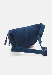 Borsa in tessuto blu navy con cintura regolabile e doppie zip su sfondo bianco.