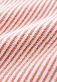 Tissu présentant des rayures fines alternées de rose clair et de blanc, avec une surface texturée et moelleuse. Le tissu affiche un aspect doux et confortable.