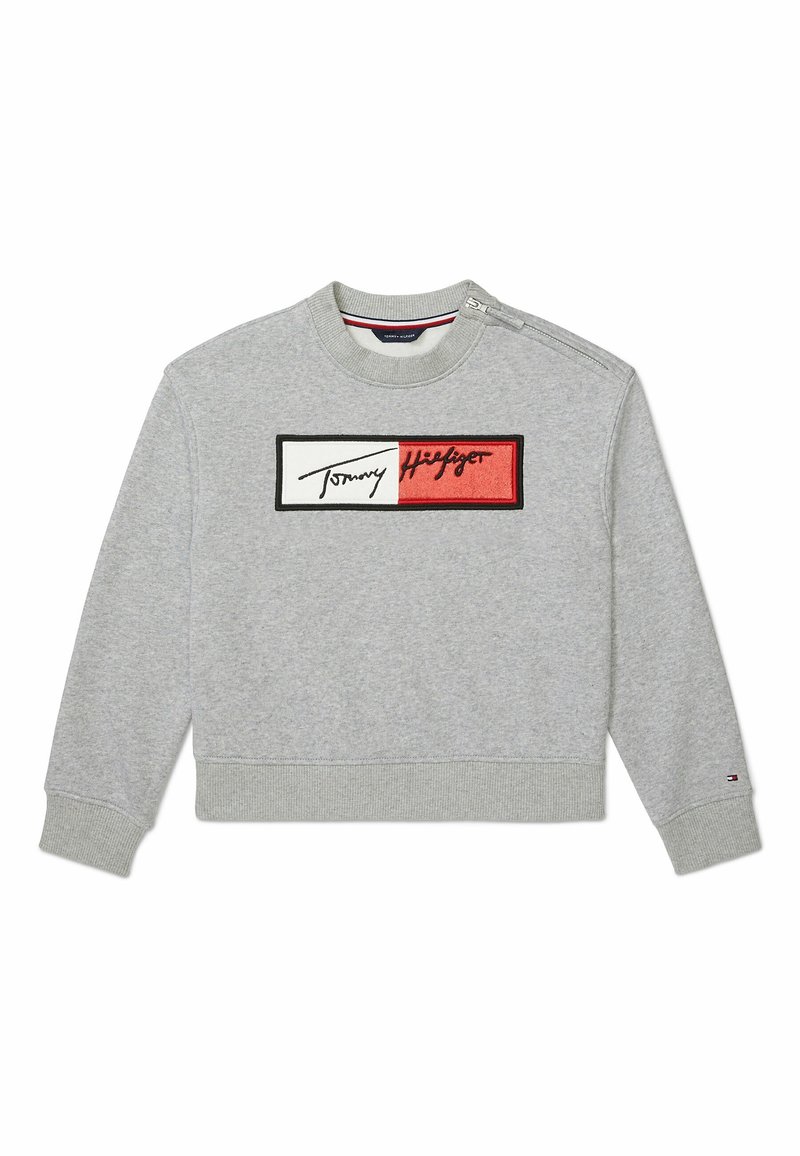 Sweatshirt gris clair à col ras du cou avec poignets, ourlet et col côtelés, arborant un patch rectangulaire rouge et blanc du logo Tommy Hilfiger sur la poitrine.