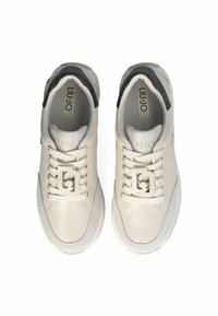 Sneakers bianchi in pelle con una texture liscia, dettagli in suede beige, design con lacci e un logo sulla linguetta. Tallone grigio a motivo.