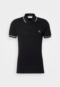 Polo noir à manches courtes avec bordure blanche au col et aux manches et petit logo blanc "cK" sur la poitrine gauche.