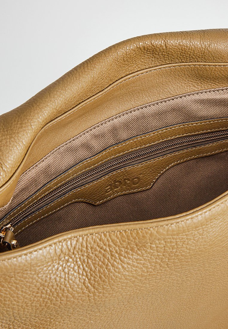 Innenseite einer braunen Ledertasche mit strukturiertem Finish, ausgestattet mit einem Reißverschlussfach und einem glatten Futter in einem helleren Farbton.