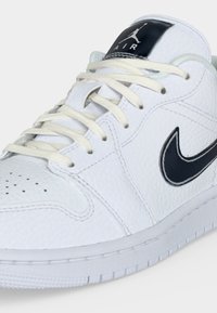 Λευκό δερμάτινο αθλητικό παπούτσι Air Jordan με μαύρο λογότυπο Nike στη πλευρά, λευκά κορδόνια και μαύρο λογότυπο Jumpman στη γλώσσα.