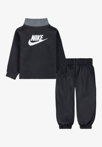 Nike schwarzer Trainingsanzug mit einem langärmligen Oberteil mit grauem Kragen und weißem Logo, kombiniert mit elastischen Hosen mit gerafften Bündchen.