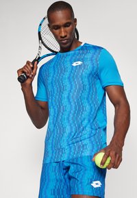 Blue sportswear set featuring a patterned short-sleeve shirt and shorts, both in varying shades of blue, with a logo and textured fabric.