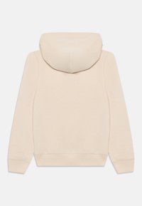 Beige mikina s kapucí, která je podšitá, má žebrované manžety a lem. Měkká textura s minimalistickým designem, vhodná pro každodenní nošení.