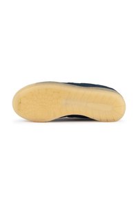 Suela de zapatilla de marino con una base de goma texturizada, que presenta patrones circulares y cuadrados; goma translúcida amarillenta en los bordes.