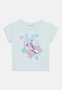 Ανοιχτό γαλάζιο κοντομάνικο μπλουζάκι με γραφικό σχέδιο ενός αθλητικού παπουτσιού με φτερά, περιτριγυρισμένο από λουλούδια σε ροζ και τιρκουάζ. Μαλακό βαμβακερό υλικό.