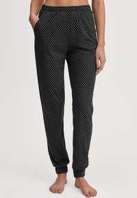Zwarte pyjamabroek met witte stippen, met elastische tailleband, zijzakken en taps toelopende boorden, gemaakt van zacht, lichtgewicht materiaal.