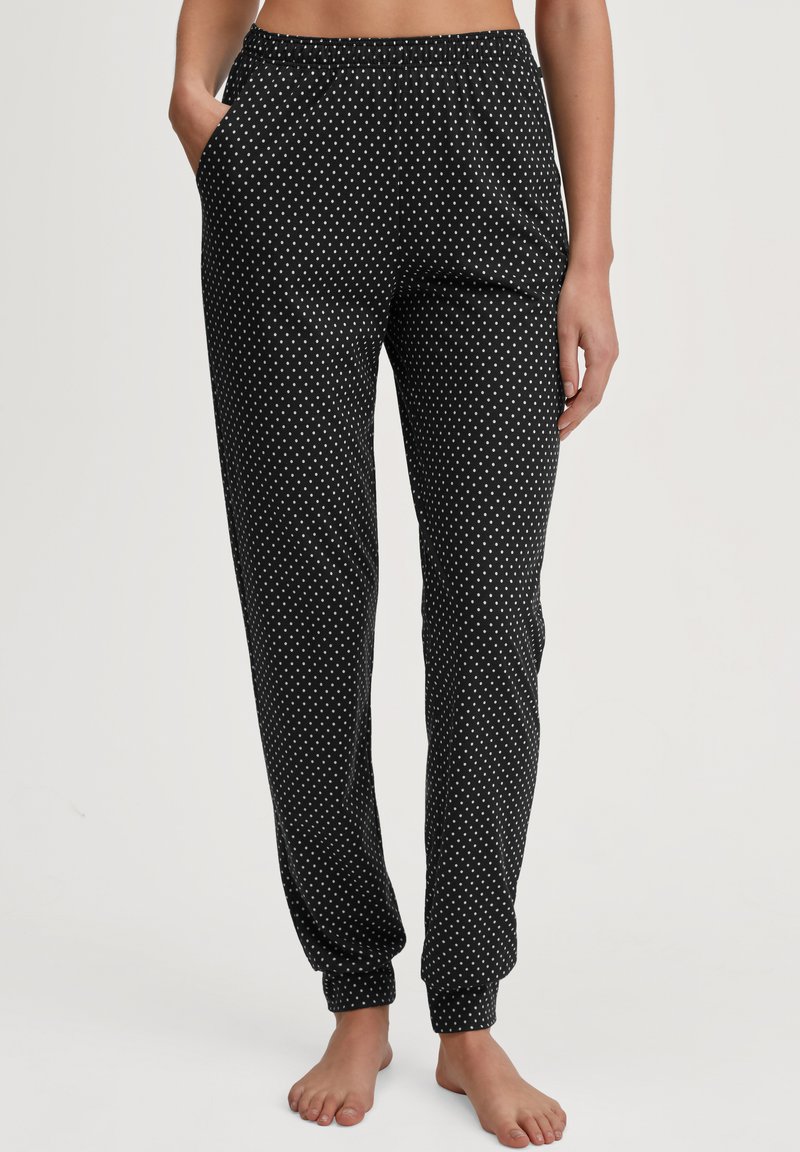 Pantalons de pyjama noirs avec des pois blancs, taille élastique, poches latérales et ourlets fuselés, fabriqués en tissu léger et doux.