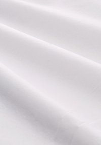 Tessuto di cotone bianco con una consistenza liscia, caratterizzato da pieghe sottili e una leggera lucentezza, disposto in un continuo ordine piegato.