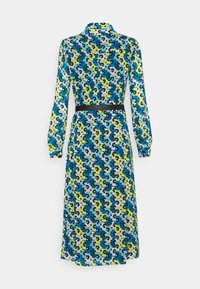 Robe à manches longues avec col, présentant un motif floral en bleu, vert, noir et blanc, cintrée à la taille avec une ceinture noire.