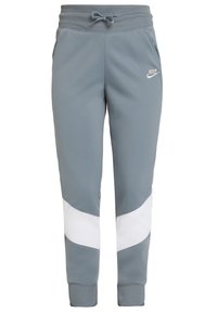 Grå Nike joggingbyxor med ett vitt diagonalt rand, elastisk midja, justerbar dragsko och sidofickor. Mjuk, slät tygkvalitet.