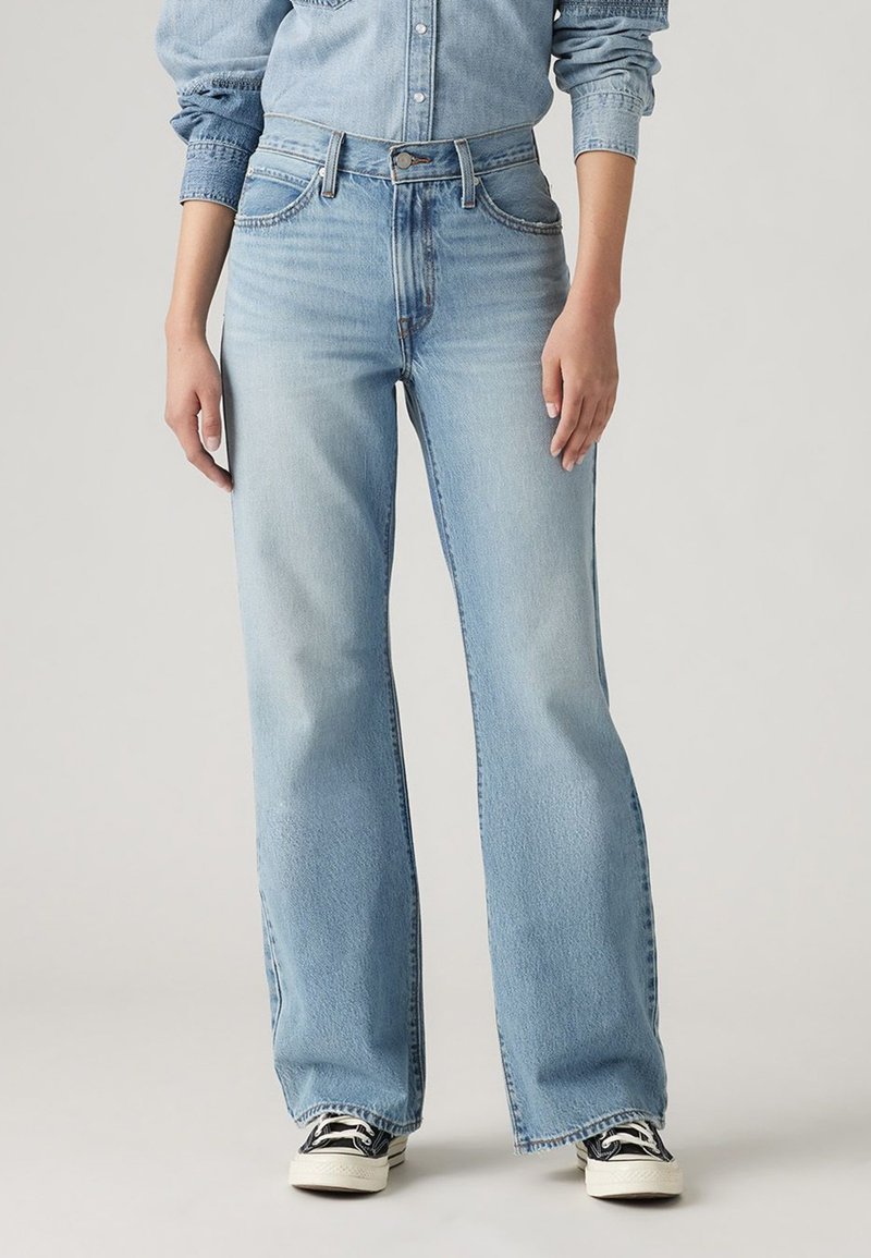 Light blue, high-waisted denim jeans with a flared silhouette. Features five pockets, contrasting stitching, and a faded wash.
