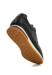 Black leather sneaker with a textured upper, elastic side panel, and a rubber sole featuring a tread pattern and white midsole.