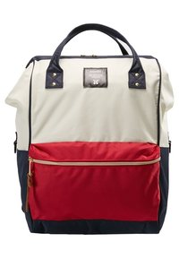 Plecak z płótna o kremowej górnej części, czerwonej dolnej sekcji i granatowych akcentach. Posiada zapinaną na zamek przednią kieszeń oraz wzmocnione uchwyty.