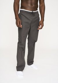 Gray relaxed-fit pants with an elastic waistband and drawstring, featuring a smooth texture. Paired with white ankle socks.