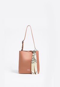 Persika naha käekott, millel on pikk reguleeritav rihm, ja mille esiotsas on kinnitatud sõlmega kreemvärvi siidist sall mustade disainiaktsentidega.