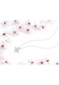 Sølv halskæde med en blomsterpendant, der har klare ædelsten. Omgivet af lyserøde kirsebærblomsterblade på en hvid baggrund.
