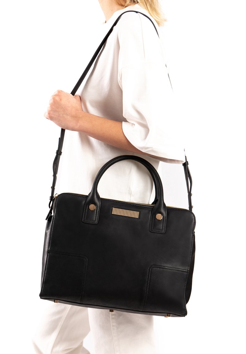 Sac à main en cuir noir avec deux poignées supérieures et une bandoulière amovible. Comprend des accents dorés et un panneau texturé à l'avant.