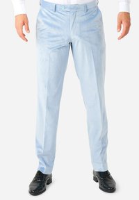 Pantalones de tela suave de color azul claro, con un corte slim, frente plano y dos bolsillos laterales, combinados con zapatos de charol negros.