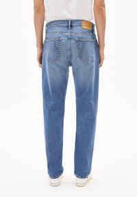 Lichtblauwe denim jeans met een ontspannen pasvorm, zichtbare stiksels, twee achterzakken en een tan leren label op de tailleband.