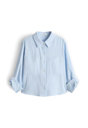 Hellblaues Langarmhemd mit Knopfleiste, zwei Brusttaschen und hochgekrempelten Ärmeln vor weißem Hintergrund.