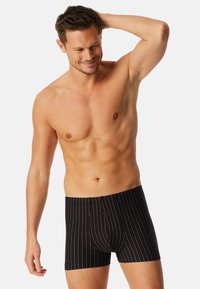 Boxers noirs avec des rayures verticales multicolores. Fabriqués dans un tissu doux et extensible, offrant un ajustement confortable et une pochette moulante.