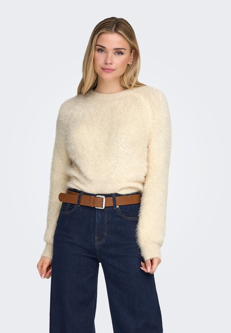 Cream-colored fluffy sweater with a round neckline and long sleeves, paired with dark blue high-waisted jeans and a brown leather belt.