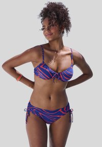Twee-delig bikini in blauw met rode wervelende patronen. Beha heeft verstelbare bandjes en een strik in het midden; het broekje heeft zijsstrikjes. Gladde textuur.