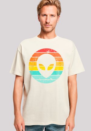 Beige T-Shirt mit einem verwitterten Retro-Aliendesign und horizontalen Streifen in Farbverläufen von Rot, Orange, Gelb und Türkis.