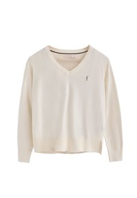 Maglione crema a scollo a V realizzato in tessuto morbido, con maniche lunghe e un piccolo logo sul petto. Dettagli testurizzati sottili all'orlo.