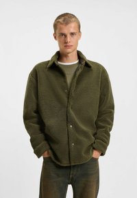 Olivgrüne Fleecejacke mit strukturiertem Finish, Knopfleiste und umklappbarem Kragen. Verfügt über lange Ärmel und eine lockere Passform.