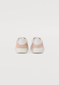 Sneaker in suede rosa chiaro con dettagli bianchi, dotate di un colletto imbottito e logo sul tallone, montate su una suola in gomma bianca.