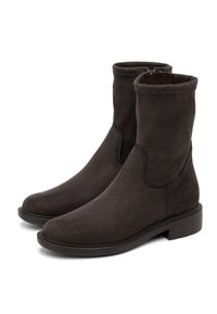 Un paio di stivali alla caviglia in suede marrone scuro con tacco basso e cerniere laterali, mostrati su uno sfondo bianco.