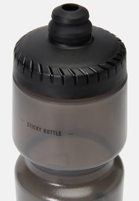 Bottiglia sportiva grigia con tappo a vite nero, impugnatura texturizzata e etichetta "STICKY BOTTLE" stampata in nero sul lato.