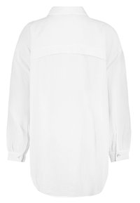 White long-sleeved shirt made from textured fabric, featuring a collar, button cuffs, and a rounded hem with a yoke.