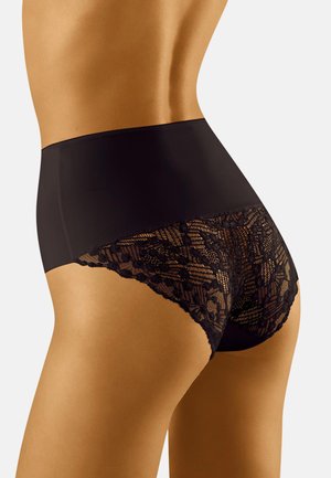 Woman wearing high-waisted black underwear with solid fabric front and floral lace detailing on the back and sides.