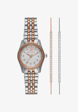 Montre en métal bicolore argent et or rose avec un cadran blanc et des index horaires en cristal, associée à des bracelets en cristal assortis en or rose et argent.