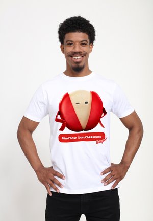 Witte t-shirt met een grote graphic van een ronde kaaswedge met rode was, tekst "Mind Your Own CheeseWax," zwarte broek.
