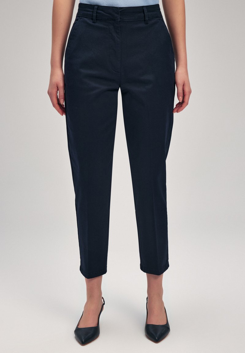 Pantaloni blu navy scuri con fit su misura, dotati di una parte anteriore piatta, tasche laterali e orlo con risvolto, realizzati in un tessuto liscio.