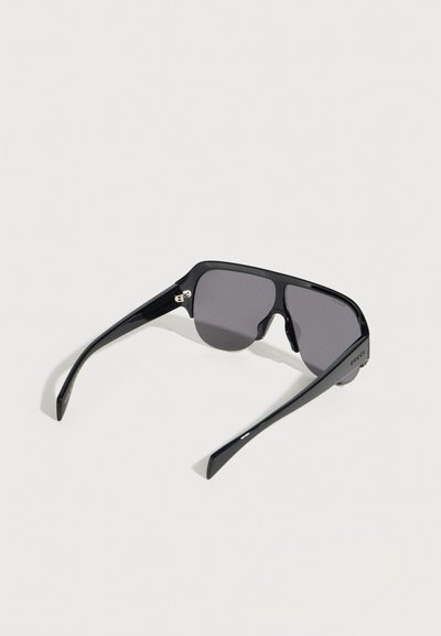 Schwarze, übergroße rechteckige Sonnenbrille mit dunklen Gläsern und dicken Bügeln, mit Gucci-Logo an der Seite.