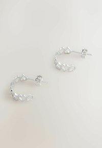 Cercei rotunzi din argint, în formă de inimi interconectate, având un finisaj lustruit și un sistem de închidere cu tijă, care pun în evidență o textura netedă și strălucitoare.