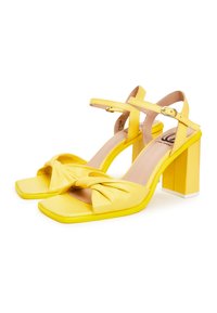 Gelbe Leder-High-Heel-Sandalen mit geknüpftem Vorderteil, quadratischer Zehenpartie und blockiertem Absatz. Verstellbarer Riemen mit Schnallen-Detail.