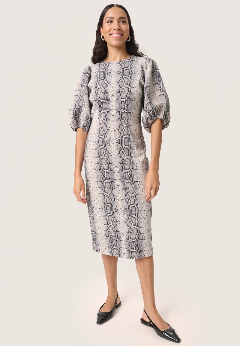 Elegant midi šaty v hadím vzore, s vyp puffovými rukávmi, okrúhlym výstrihom a priliehavým strihom. Nosí sa s čiernymi špicatými topánkami.